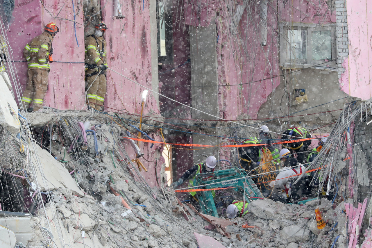 Rescue workers search for missing workers among debris at a collapsed apartment building in the southwestern city of Gwangju on Friday. (Yonhap)