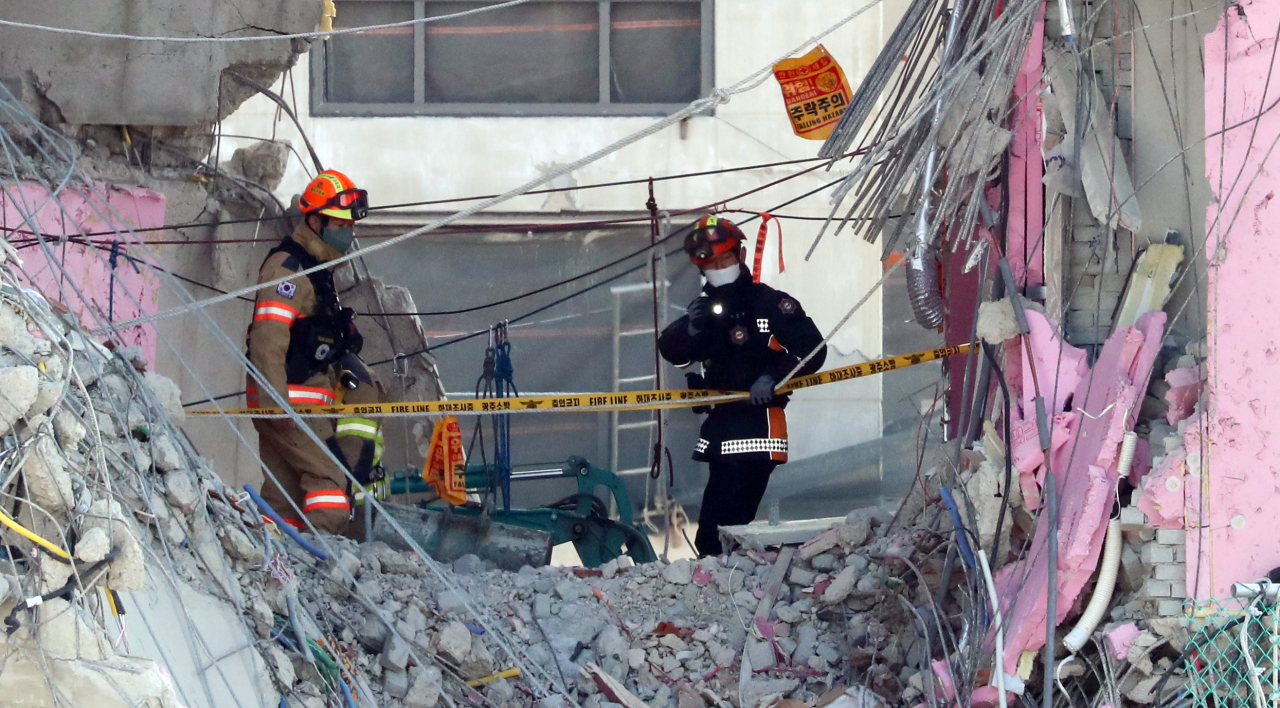 Rescue personnel search for two trapped and missing workers among debris at a collapsed apartment building in the southwestern city of Gwangju on Sunday. The high-rise apartment building under construction collapsed on Jan. 11. (Yonhap)