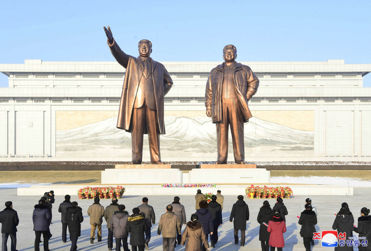 This file photo, captured from North Korea's Central TV, shows North Korean people and soldiers offering flowers in front of the statues of late North Korea founder Kim Il-sung and his late son Kim Jong-il in Pyongyang on the occasion of the 74th founding anniversary of the Korean People's Army on Tuesday. (North Korea's Central TV)