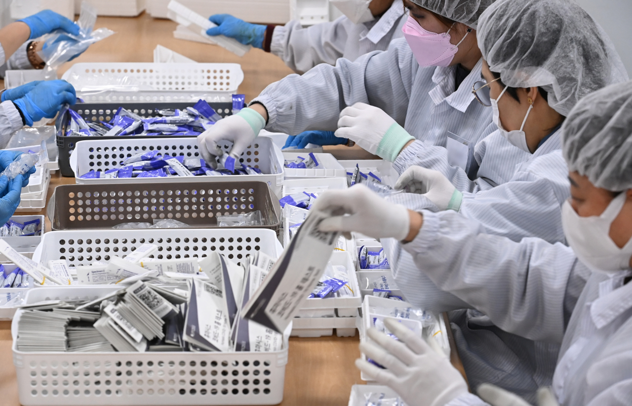 Employees work on a COVID-19 testing kits production line at Humasis in Gunpo, Gyeonggi, Wednesday. (Yonhap)