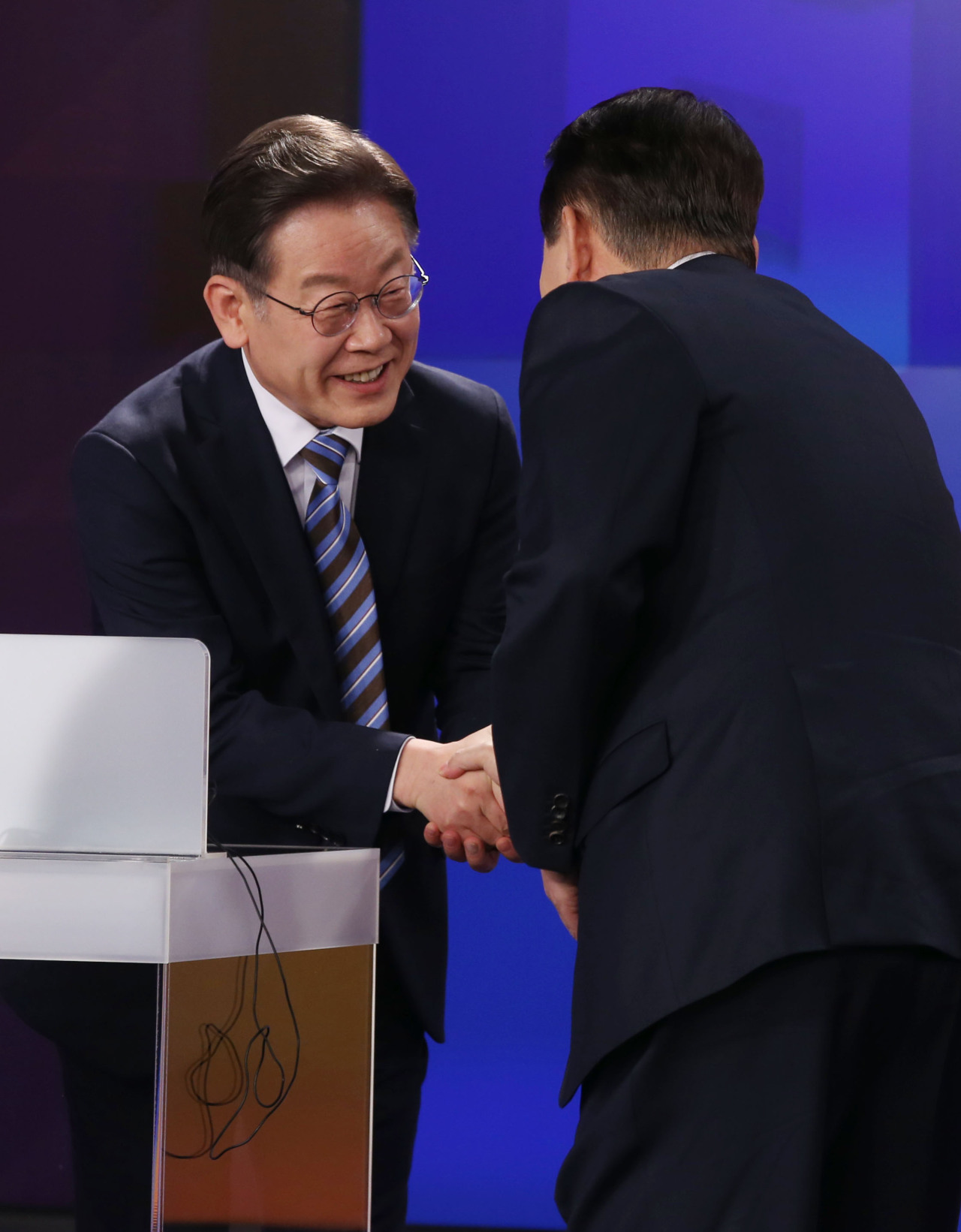 Presidential candidates Lee Jae-myung (left) and Yoon Suk-yeol shake each other`s hand before Friday`s TV debate. (Joint Press Corps)