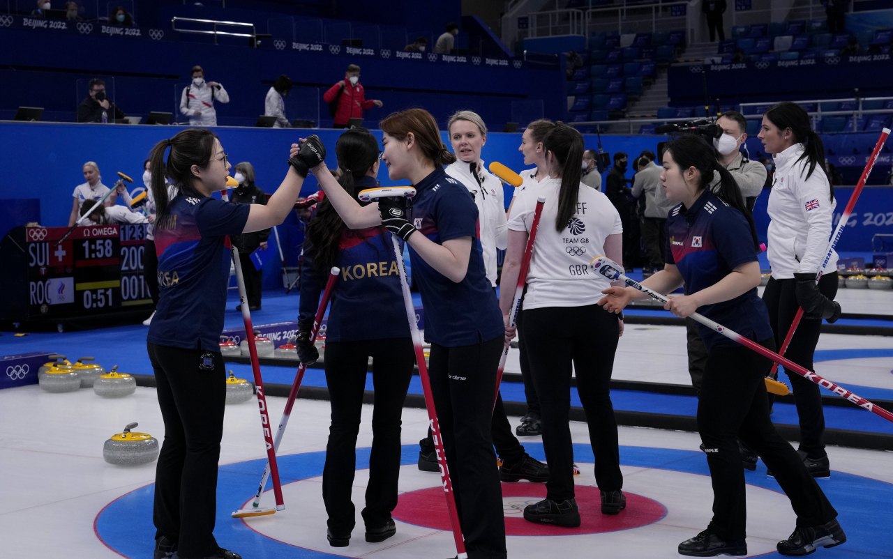 South Korea's Kim Seon-yeong, left, and Kim Cho-hi, shake hands after winning the women's curling match against Britain, at the 2022 Winter Olympics, last Friday, in Beijing. (AFP-Yonhap)