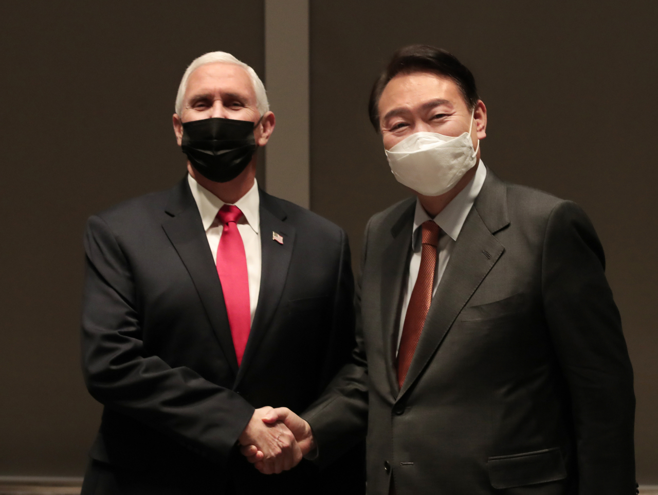 In this photo provided by the main opposition People Power Party (PPP), Yoon Suk-yeol (R), the presidential candidate of the conservative PPP and former US Vice President Mike Pence shake hands before a meeting in Seoul on Sunday. (PPP)