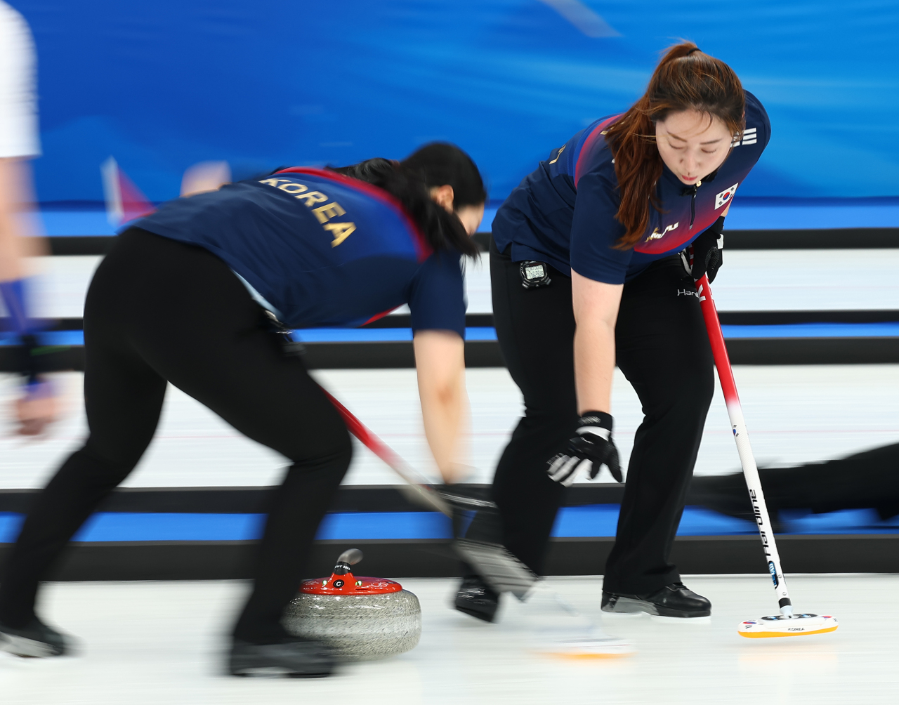 Kim Yeong-mi (L) and Kim Kyeong-ae of South Korea sweep the ice during a round-robin game against China in the women's curling tournament at the Beijing Winter Olympics at the National Aquatics Centre in Beijing on Sunday. (Yonhap)