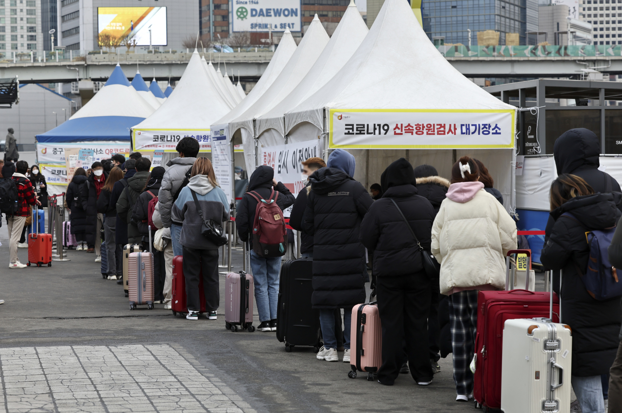 People wait in line to receive tests at a COVID-19 testing station in Seoul on Monday, when the country reported 54,619 new cases. (Yonhap)