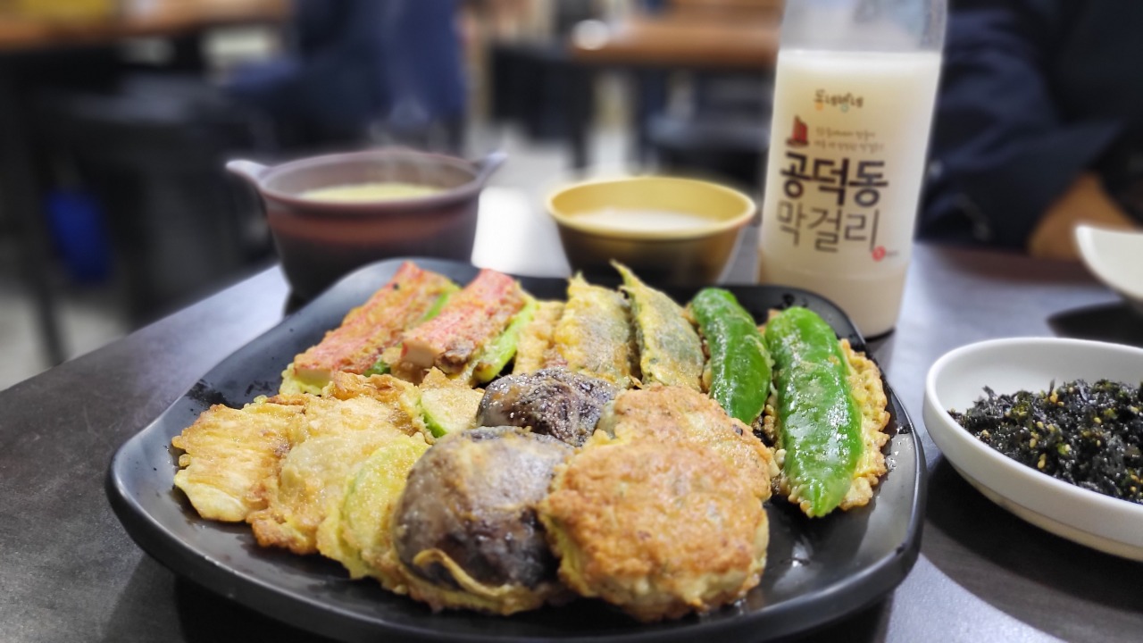 A set of medium-sized modeumjeon (assorted jeon) and Gongdeok makgeolli are served at Moisae Buchimgae in Gongdeok Market. (Kim Hae-yeon/The Korea Herald)