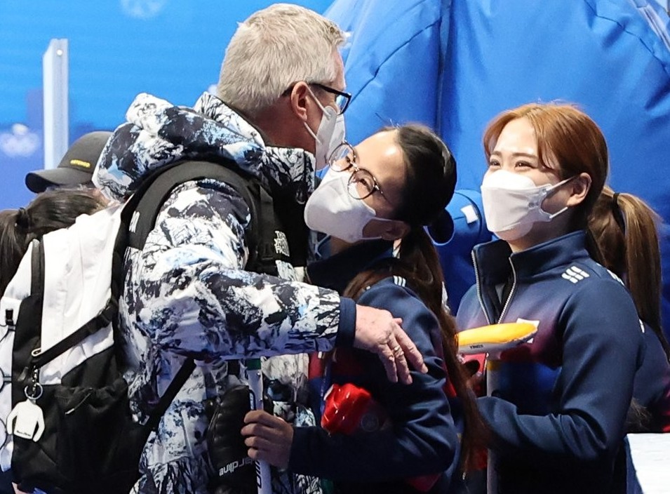 South Korea coach Peter Gallant (L) and skip Kim Eun-jung share an embrace after South Korea's 8-4 loss to Sweden in a women's curling round-robin game at the Beijing Winter Olympics at the National Aquatics Centre in Beijing on Feb. 17, 2022. (Yonhap)