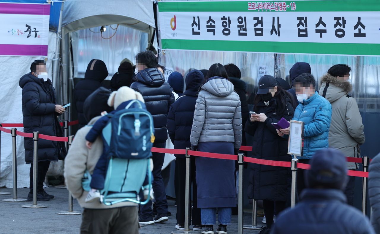 People wait in line for a COVID-19 test at a testing site set up near the Seoul Station in central Seoul, Sunday. (Yonhap)