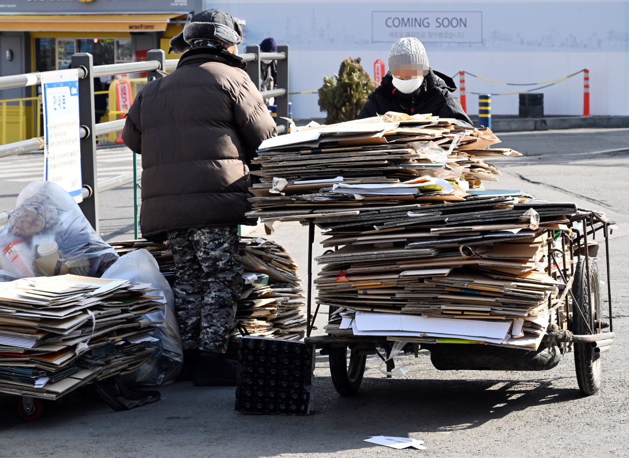 Homeless people haul a cart of cardboard scrap near Seoul Station on Wednesday. (Park Hyun-koo/The Korea Herald)