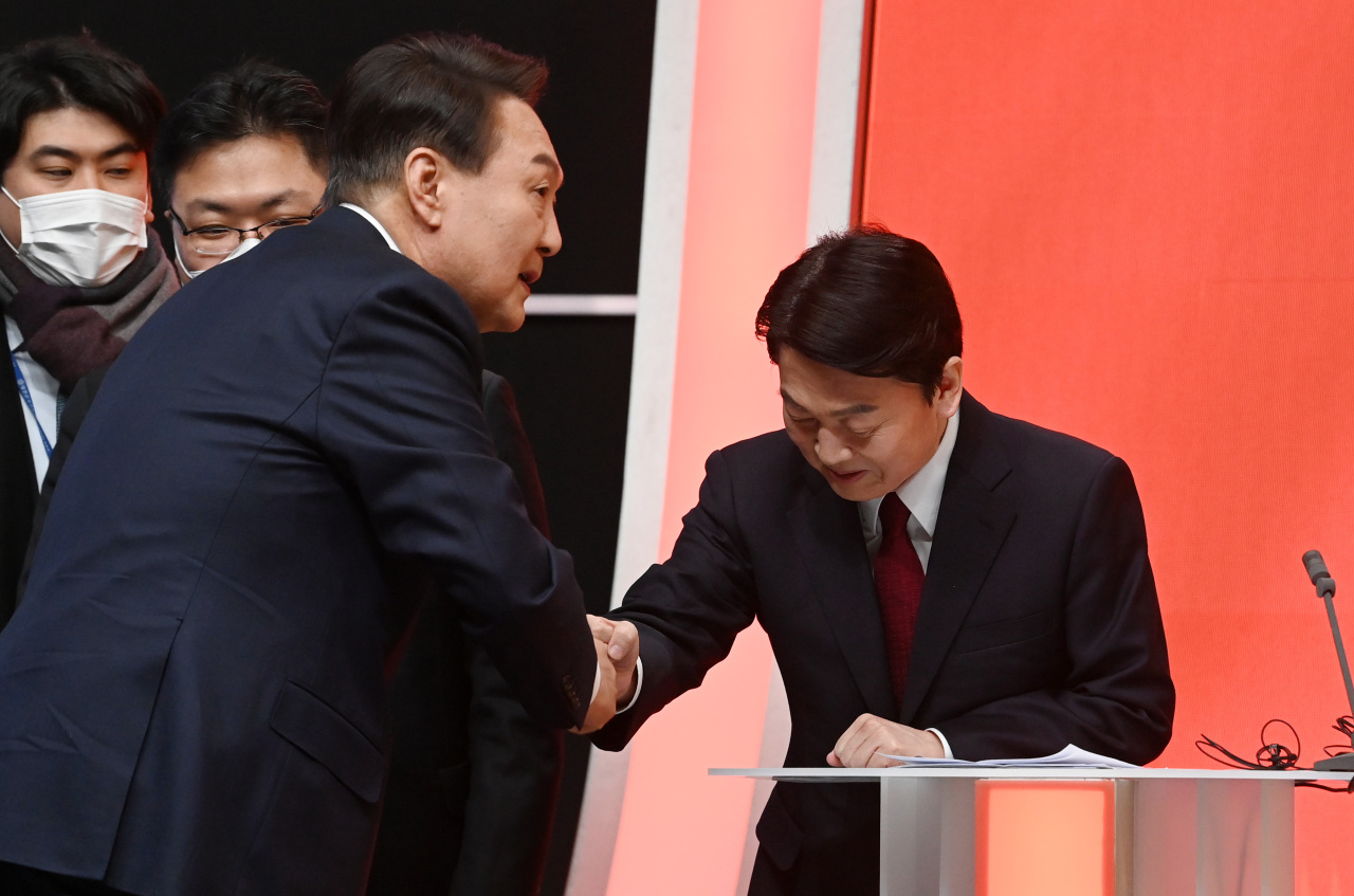 Yoon Suk-yeol, candidate of the main opposition People Power Party (left) and Ahn Cheol-soo, the opposition People’s Party’s nominee, greet each other before a TV presidential election debate held Monday. (Yonhap)