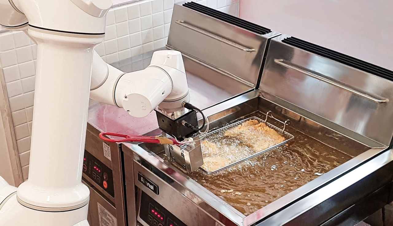 A robot arm puts a bucket full of frozen chicken in the frying machine at the Roboarte headquarters in Gangnam, Seoul. (GS Retail)
