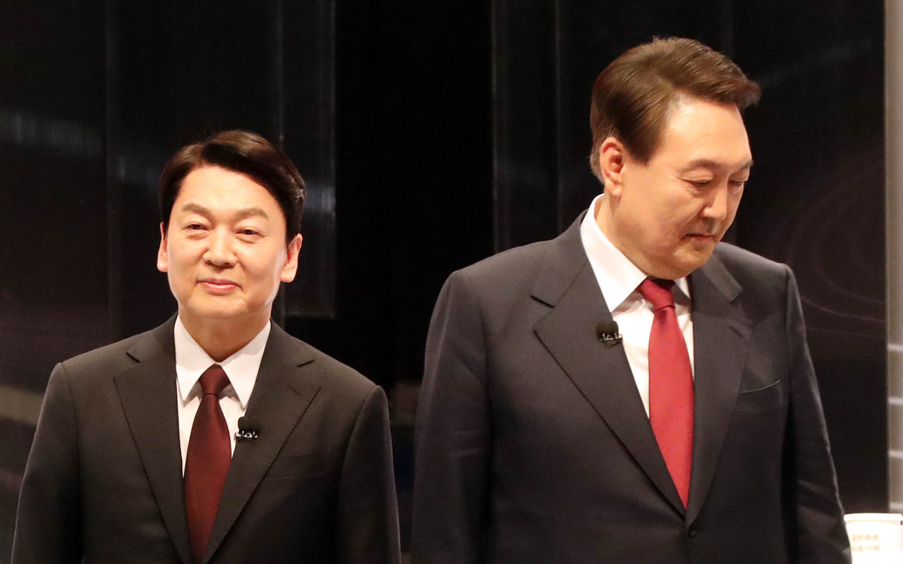 Ahn Cheol-soo, the presidential candidate for the minor opposition People’s Party and Yoon Suk-yeol, from the major opposition People Power Party (left) exchange greetings before a TV debate held Friday (Yonhap)