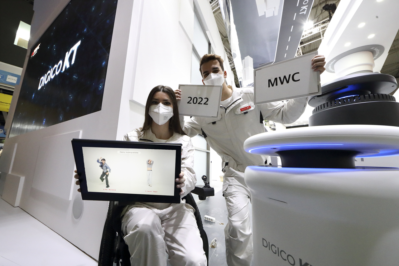 Models pose for a photo with a robot at KT‘s exhibition in Barcelona, Spain during Mobile World Congress 2022 (KT)