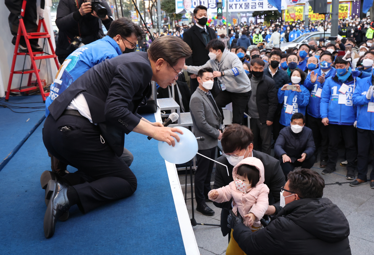 Lee Jae-myung, the presidential candidate of the ruling Democratic Party, accepts a balloon from a child during a campaign rally in Yangsan, South Gyeongsang Province, on Sunday. (Yonhap)