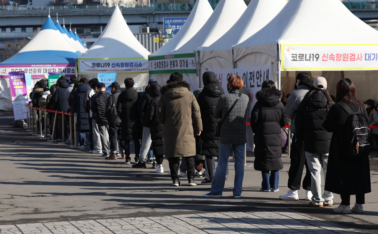 People line up to receive COVID-19 tests in front of a makeshift testing station on Sunday. (Yonhap)