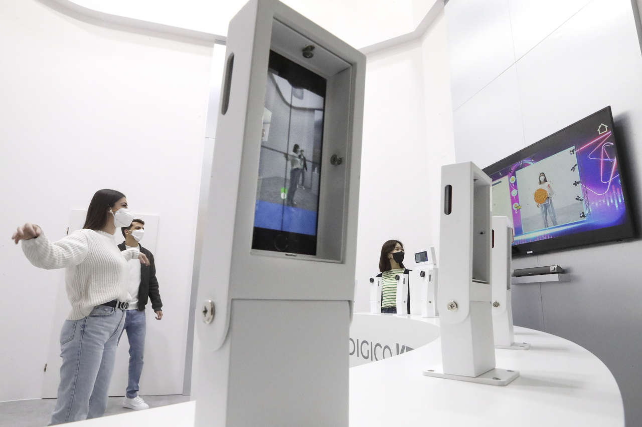 A visitor follows dance instruction provided by an app developed by KT at its exhibition booth at the World Mobile Congress in Barcelona, Monday. (KT Corp.)