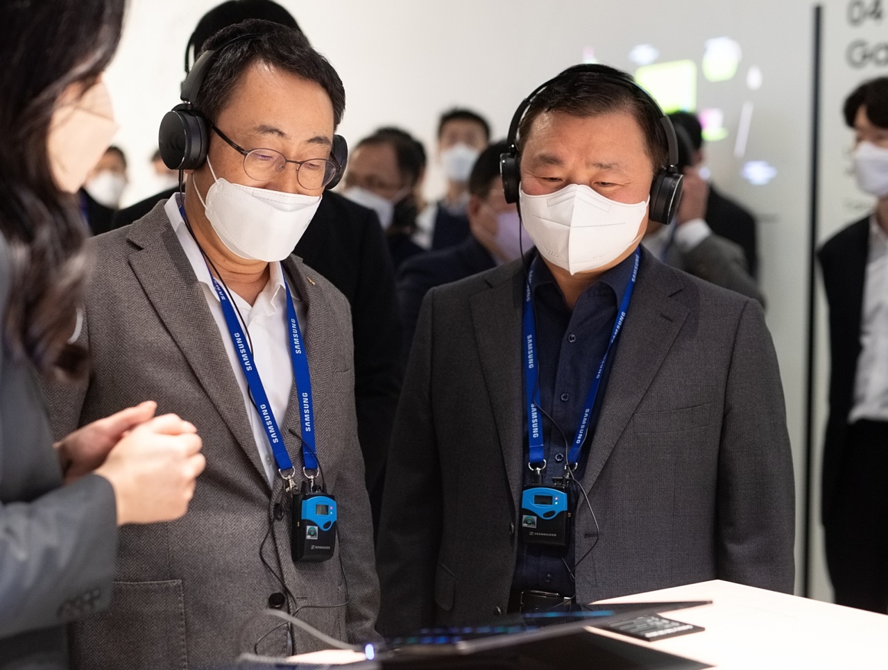 Samsung Electronics president and head of Mobile eXperience business, Roh Tae-moon, (right) and SK Telecom Chief Executive Officer Ryu Young-sang are seen during a tour of Samsung’s exhibition at MWC 2022 in Barcelona, Spain, Monday. (Join Press Corps.)