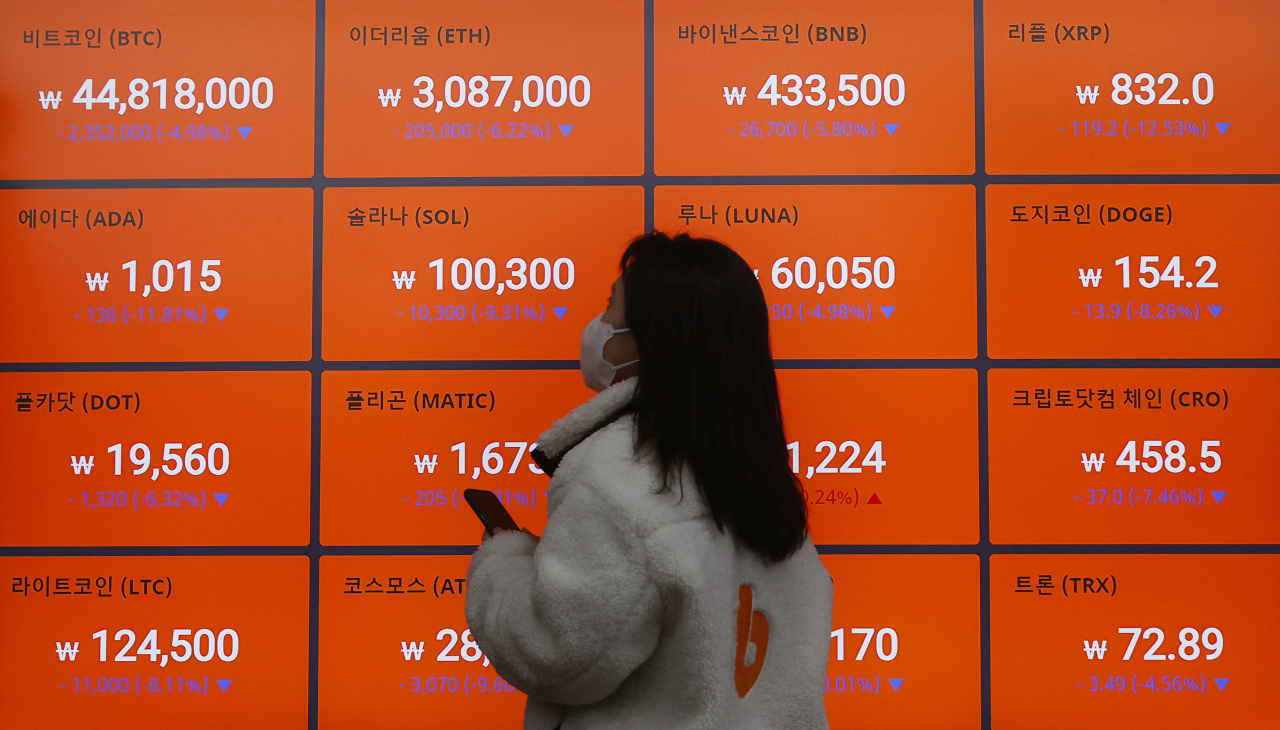 A woman stares at a giant electronic signboard displaying the trading information of different virtual currencies at a cryptocurrency exchange in Seoul. (Yonhap)