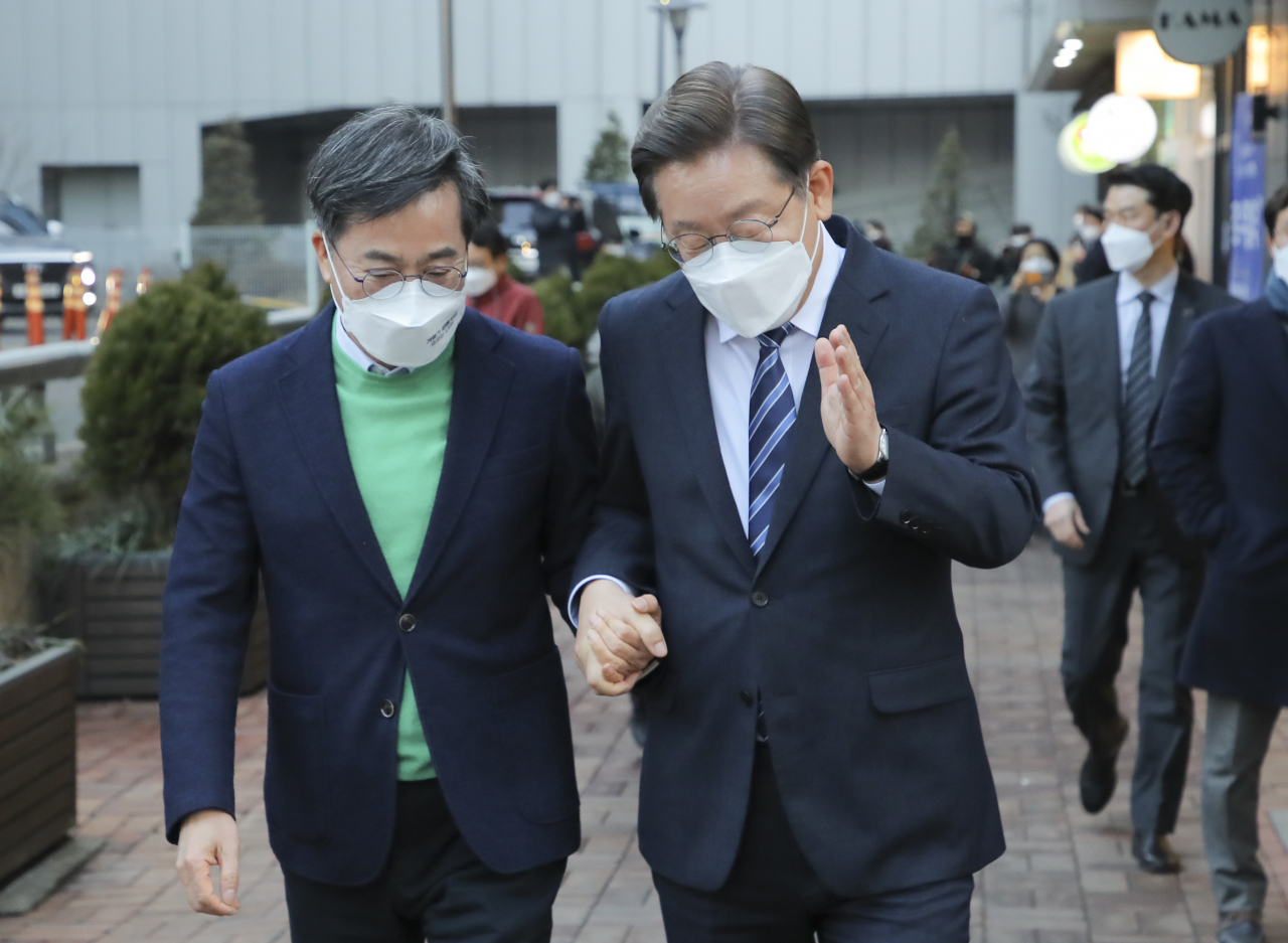Lee Jae-myung (R), the presidential candidate of the ruling Democratic Party, and Kim Dong-yeon, the presidential nominee of the New Wave Party, hold hands following their meeting at a cafe in Seoul on Tuesday. The two agreed to have policy coalitions for the March 9 presidential election. (Yonhap)