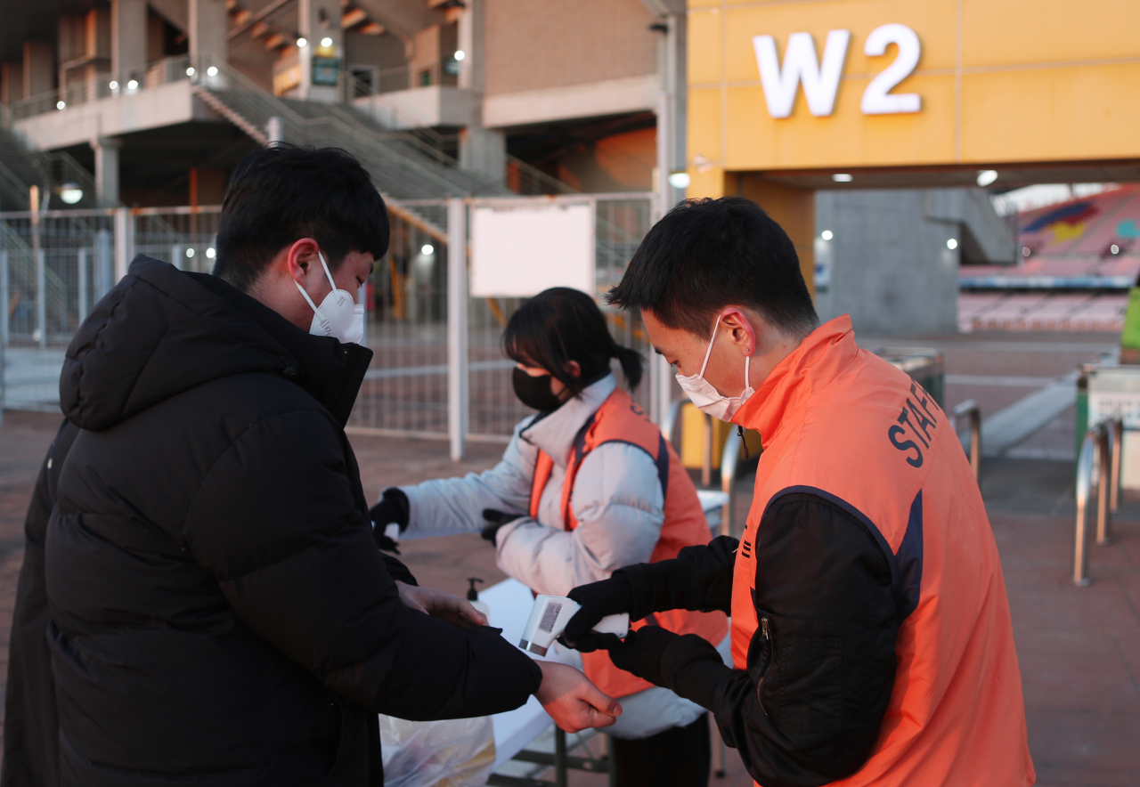 Workers check the temperatures of people entering Jeonju World Cup Stadium in Jeonju, 243 kilometers south of Seoul, on Wednesday, the day after the government suspended the enforcement of the vaccine pass system. (Yonhap)