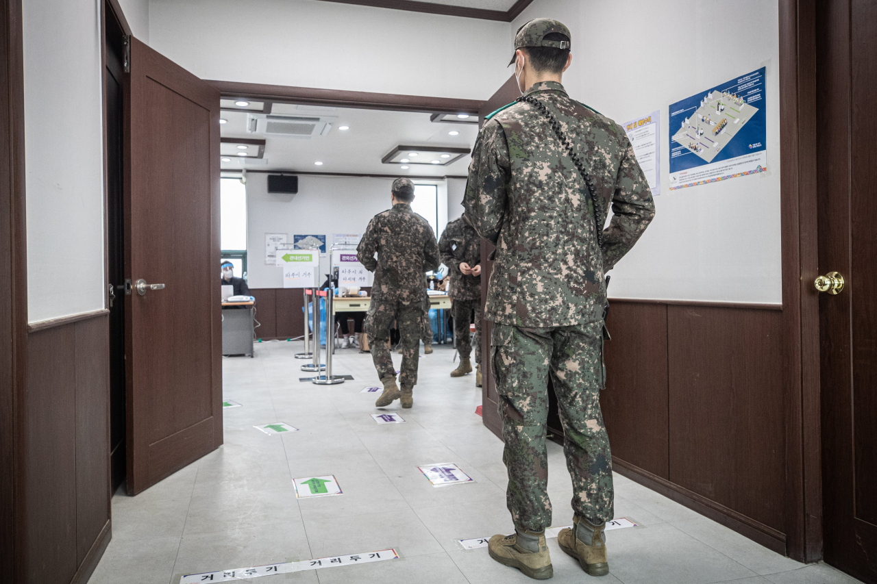 Frontline troops wait in line to cast early votes at a polling station in Paju, some 30 kilometers northwest of Seoul, on Friday. (Yonhap)