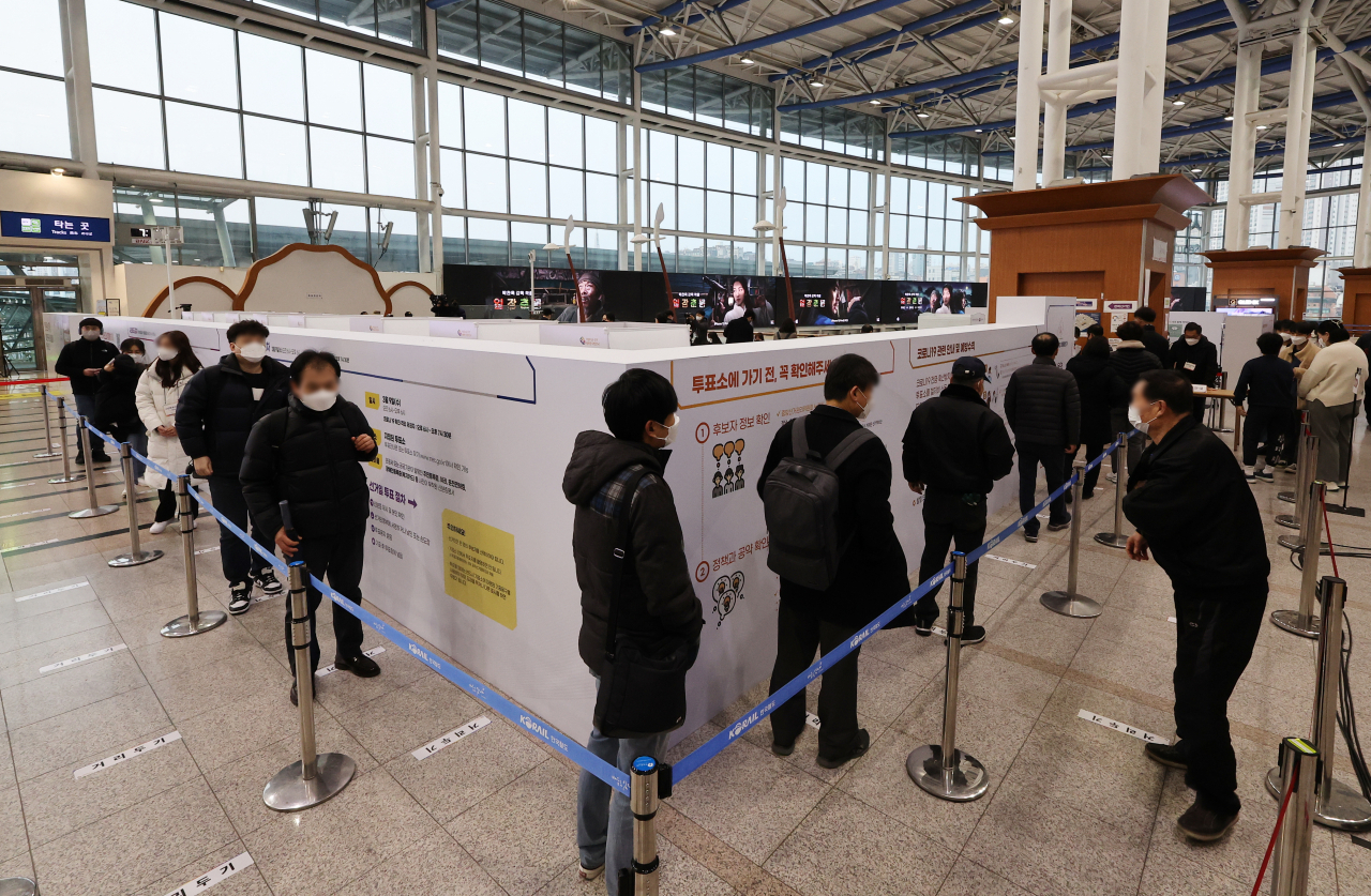 Voters stand in line to cast their ballots at a polling station in Seoul Station on Thursday, the first day of two-day early voting for the March 9 presidential election. (Yonhap)