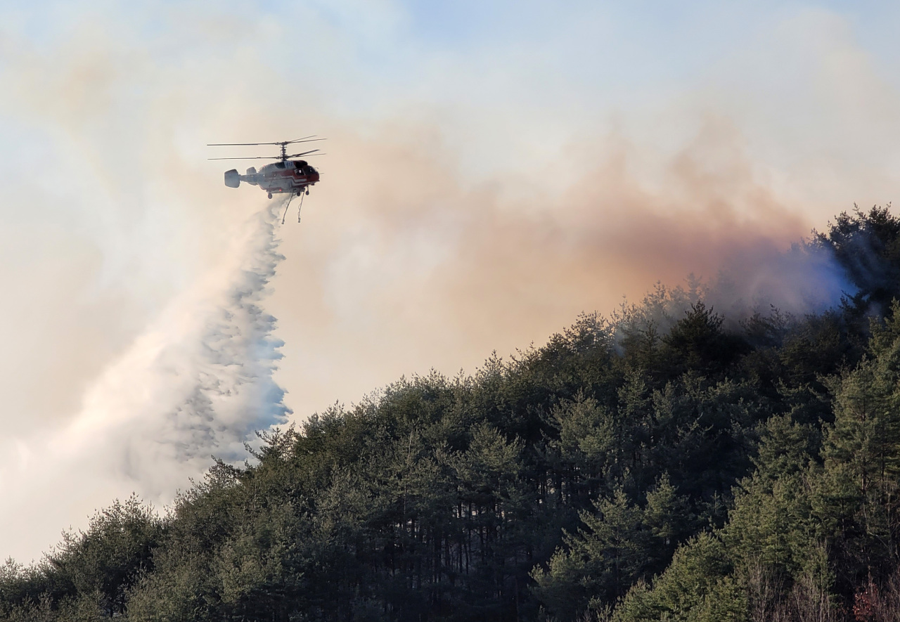 A firefighting helicopter dumps water on a hill in the eastern city of Samcheok, Gangwon Province, on March 5, 2022, to put out a wildfire that has ravaged the area since the previous day. (Yonhap)