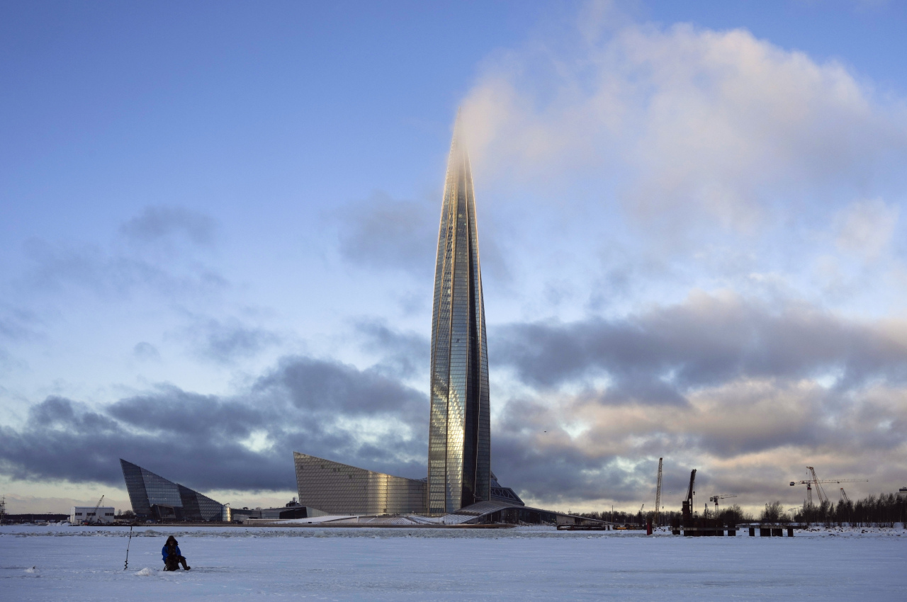 A man fishes on the ice of Finnish Gulf next to the business tower Lakhta Centre, the headquarters of Russian gas monopoly Gazprom covered by clouds in St. Petersburg, Russia, on Jan. 13, 2022. (AP)