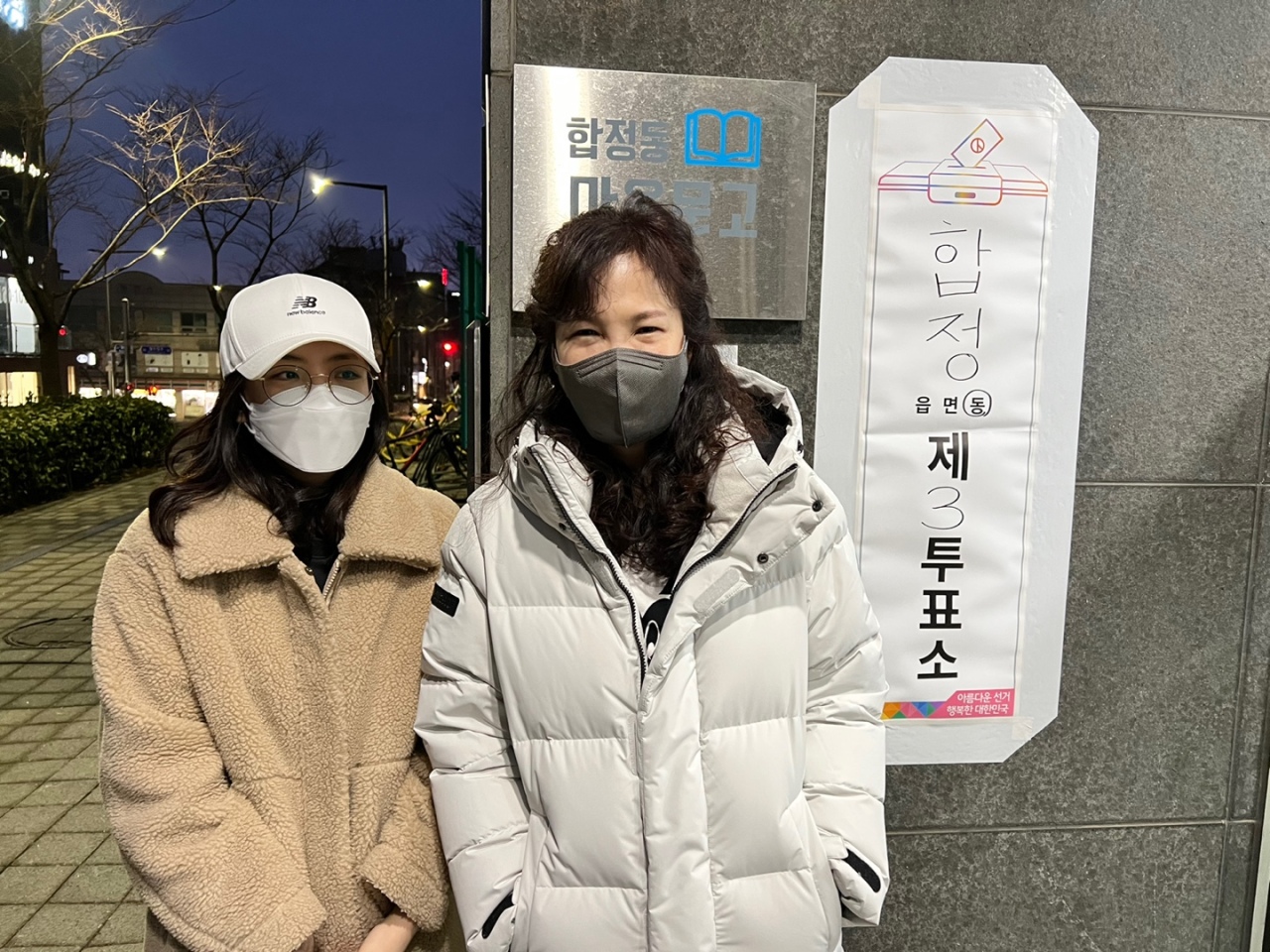 A mother and a daughter pose in front of a polling station after casting their ballots in Mapo-gu, western Seoul, in the early hours on Wednesday. (Jo He-rim/The Korea Herald)