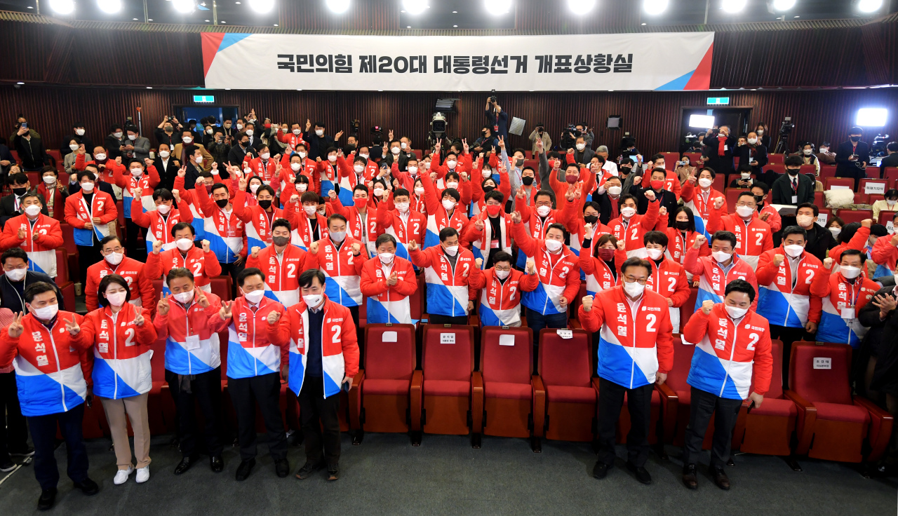 Main opposition People Power Party members raise their fists in celebration after its presidential nominee Yoon Suk-yeol took a lead in the poll as the ballot count progressed to dawn on Thursday.