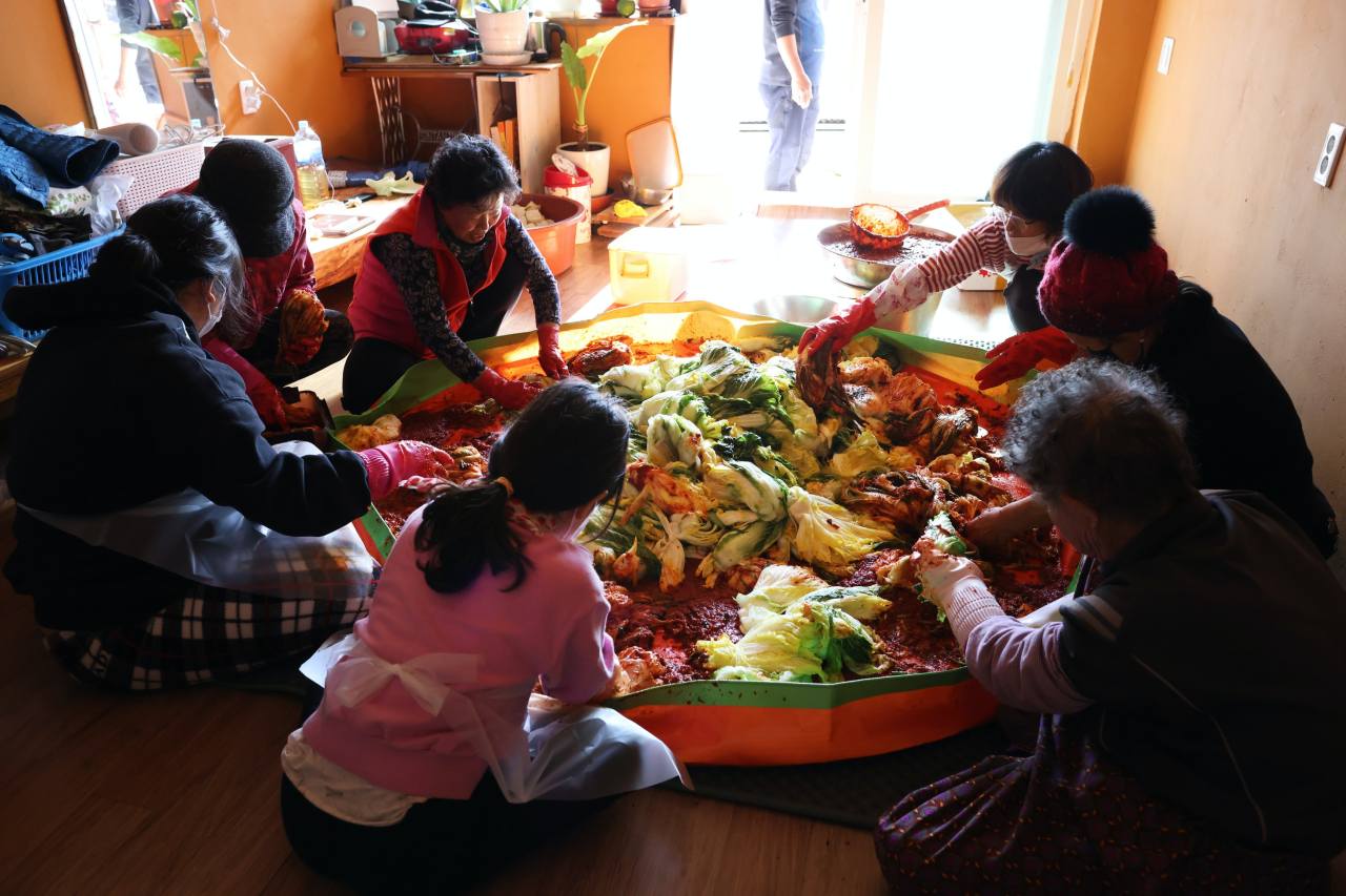 Family and friends sit around a kimchi mat to stuff leaves of the salted cabbage with a spicy sauce and stuffing mixture in Yeongyang county, North Gyeongsang Province. Photo © Hyungwon Kang