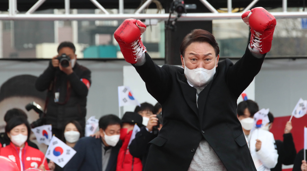 Yoon Suk-yeol performs an uppercut gesture wearing gloves presented by a boxer at a campaign event in Seoul on March 1. (Yonhap)