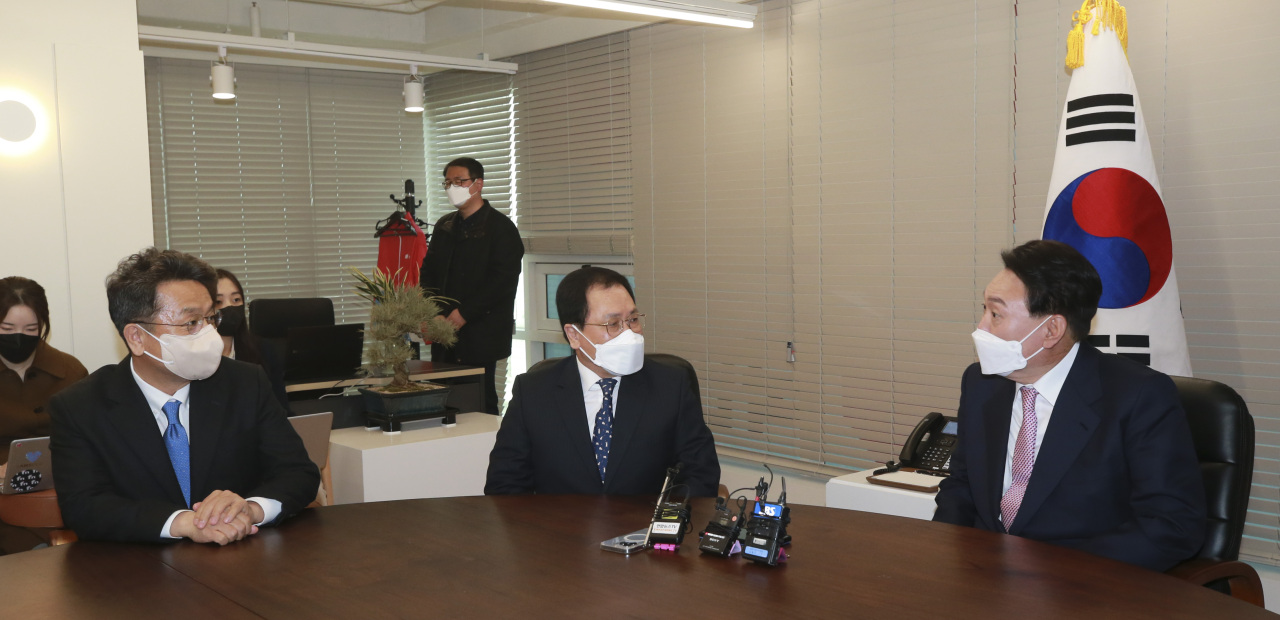 President-elect Yoon Suk-yeol (R) talks with presidential chief of staff You Young-min (C) and Lee Cheol-hee, chief presidential secretary for political affairs, after receiving a congratulatory pot of orchids from President Moon Jae-in at the People Power Party's headquarters in Seoul on Thursday. (Yonhap)