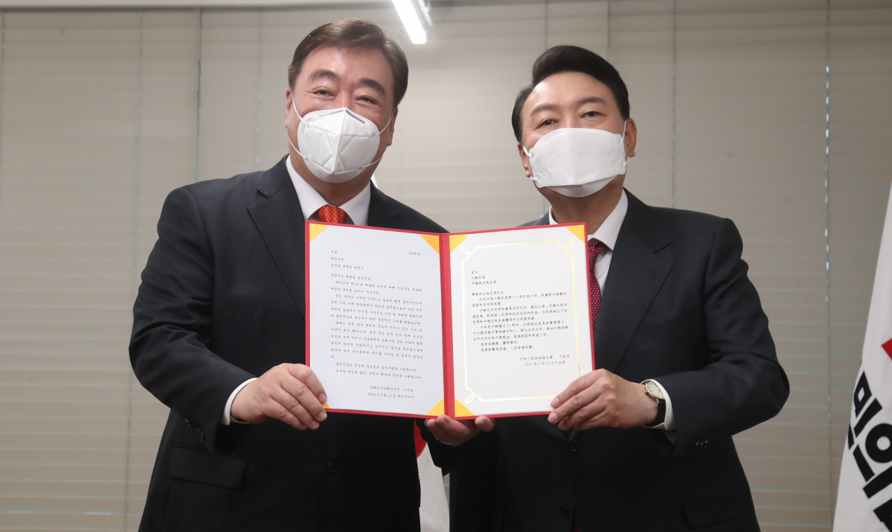 President-elect Yoon Suk-yeol (R) poses for a photo with Chinese Ambassador to South Korea Xing Haiming during their meeting at the headquarters of the main opposition People Power Party in Seoul on Friday, after receiving a congratulatory letter on Yoon's election as South Korea's next leader from Chinese President Xi Jinping. (Yonhap)