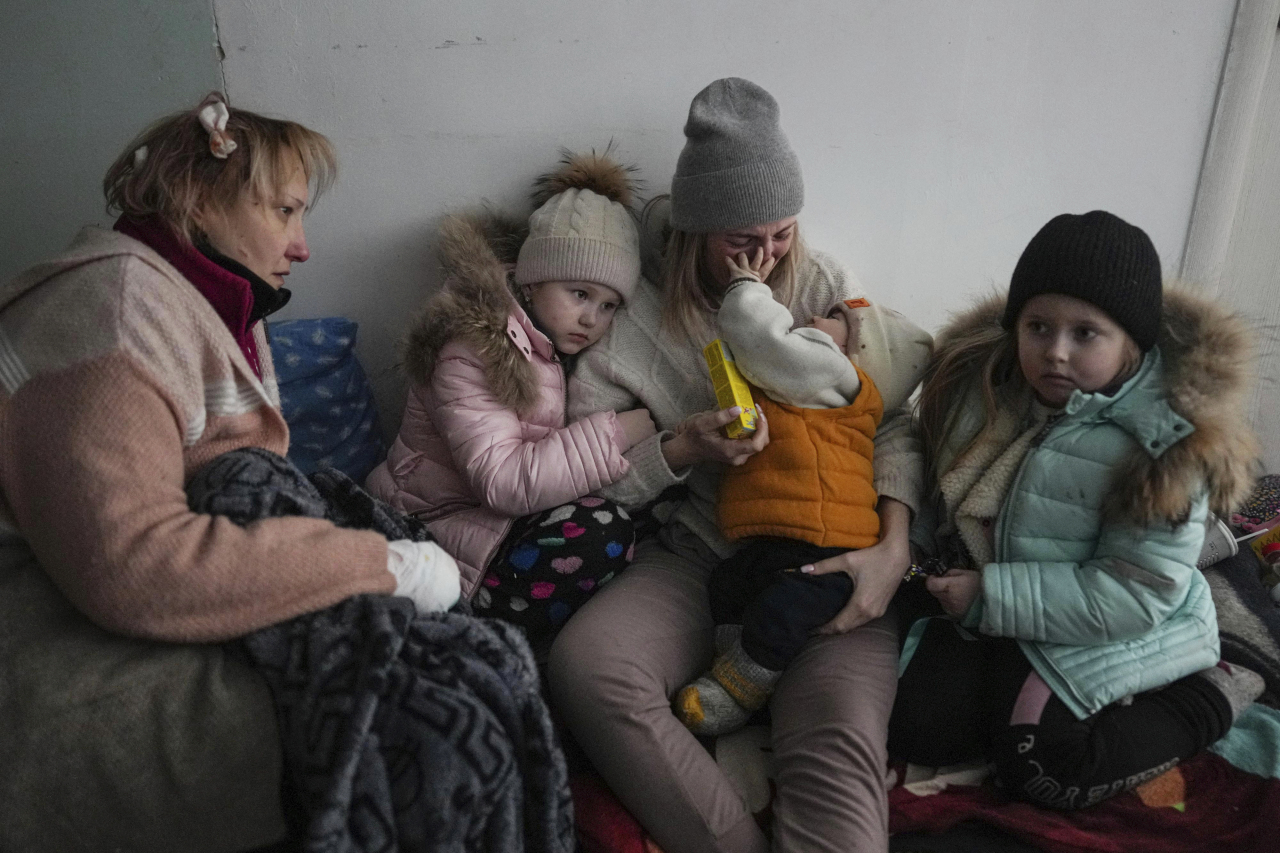 Women and children sit on the floor of a corridor in a hospital in Mariupol, eastern Ukraine on Friday. (AP Photo/Evgeniy Maloletka)