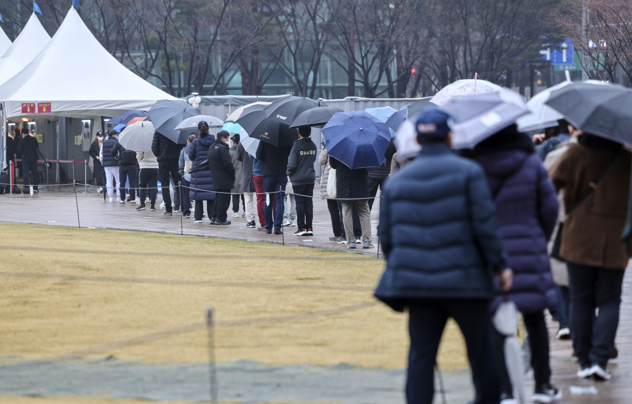 People line up for COVID-19 tests at a testing facility located in central Seoul, Sunday. (Yonhap)