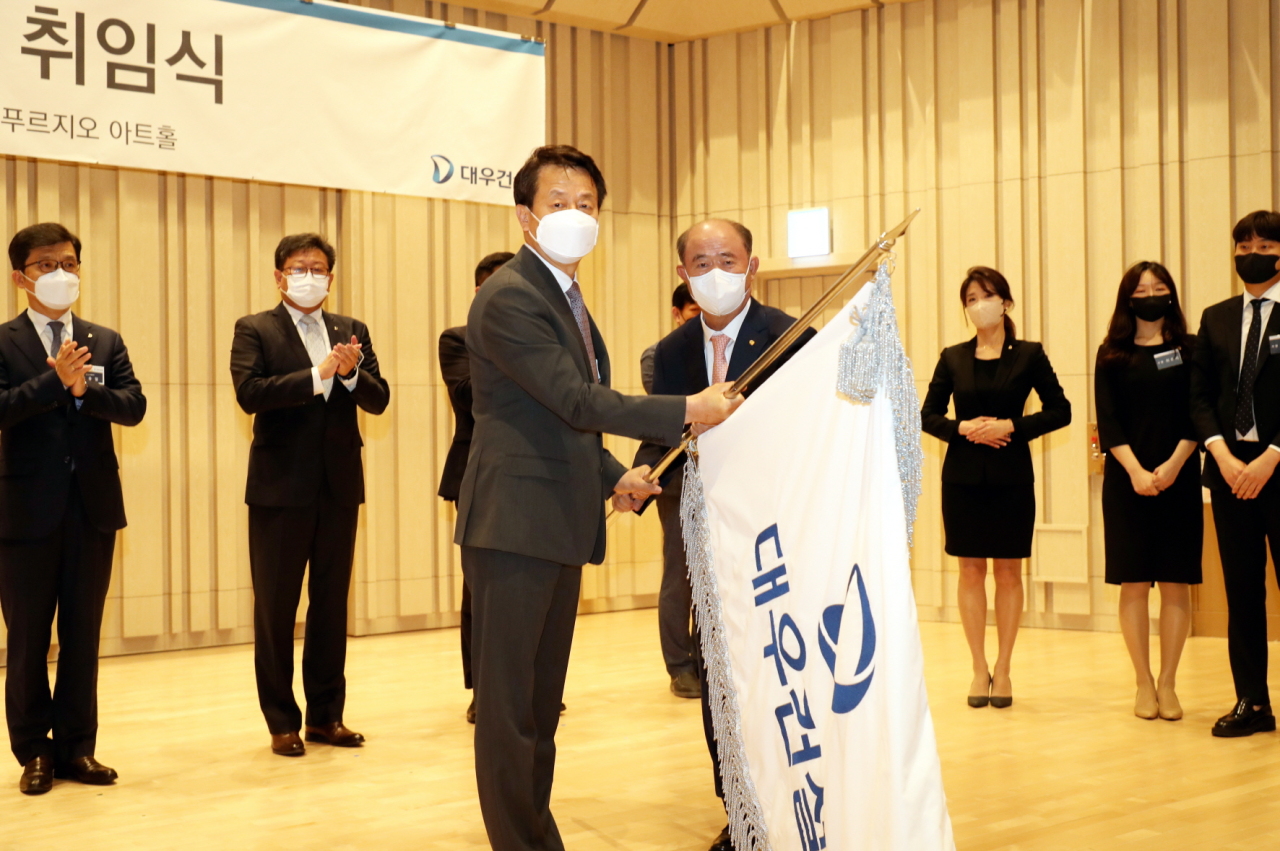 Baek Jung-wan (front left), new chief of Daewoo Engineering & Construction, and Jungheung Group Chairman Jung Chang-sun hold the Daewoo flag at an inauguration ceremony in Seoul on Wednesday. (Daewoo E&C)
