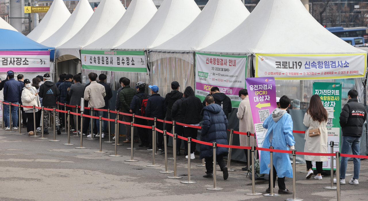 People line up to take a rapid antigen test at a testing center near Seoul station on Tuesday morning. (Yonhap)