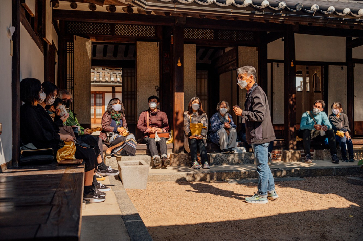 Visitors listen to a docent talking about hanok at Buckchon Hanok Village (Seoul Metropolitan Government)