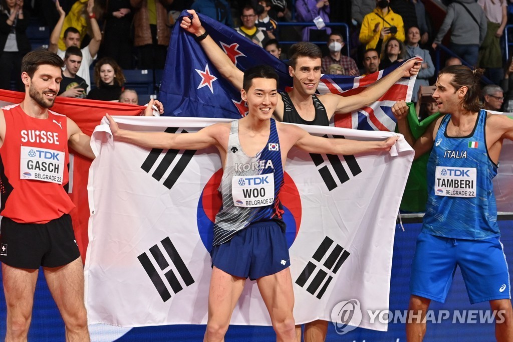 In this AFP photo, Woo Sang-hyeok of South Korea (C) celebrates after winning gold in the men's high jump at the World Athletics Indoor Championships at Stark Arena in Belgrade on March 20, 2022. (Yonhap)