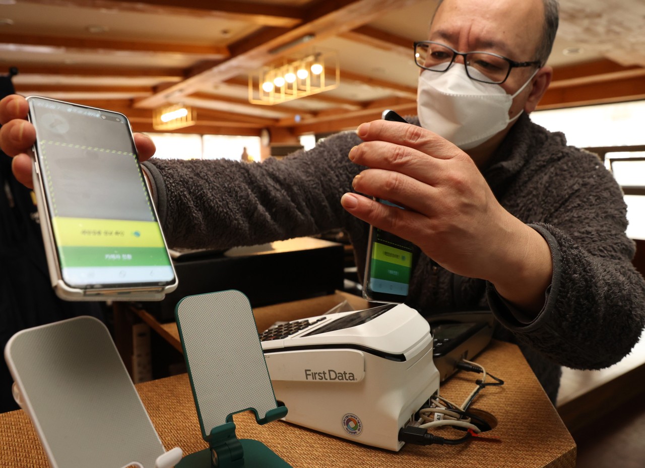An owner of a restaurant in Seoul’s Jongno-gu dismounts digital devices that had been used for a QR code entry log system on Feb. 28, as authorities announced the lifting of the vaccine pass from March 1. (Yonhap)