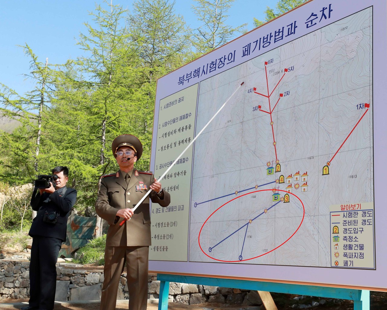 Kang Kyong-ho, deputy chief of North Korea‘s Nuclear Weapons Institute, explains the process of dismantling the Punggye-ri nuclear test site to foreign reporters on May 24, 2018. The circle shows Tunnel 3, or the South Portal, which North Korea has recently begun restoring. (Yonhap)