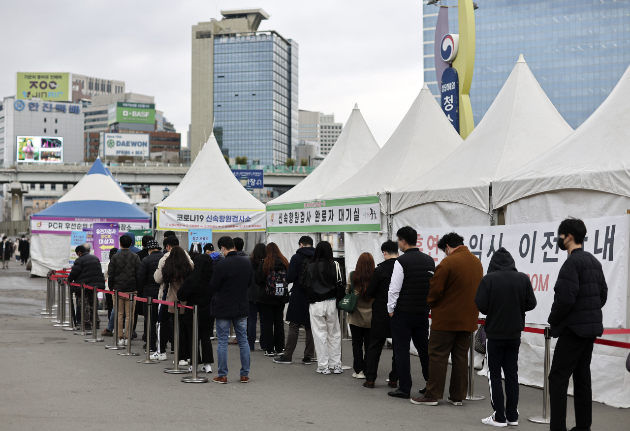 People line up at makeshift COVID-19 testing booths near Seoul Station on Thursday. (Yonhap)