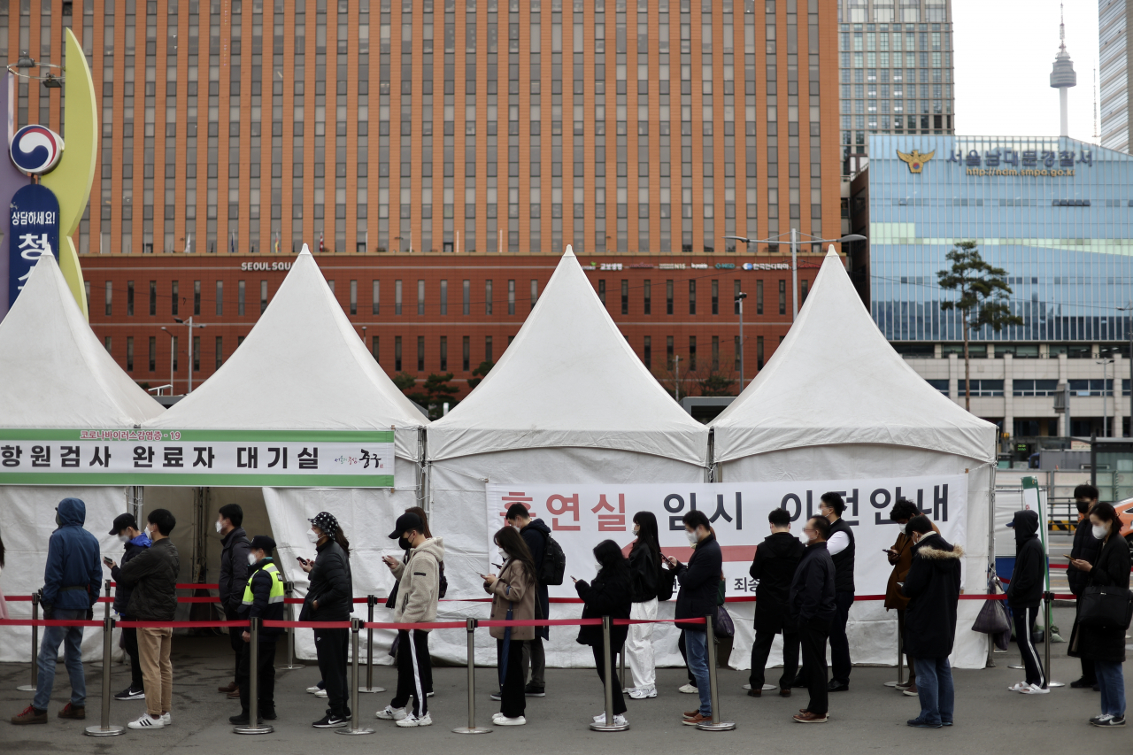 People stand in line to take coronavirus tests at a screening clinic in front of Seoul Station on Thursday. (Yonhap)