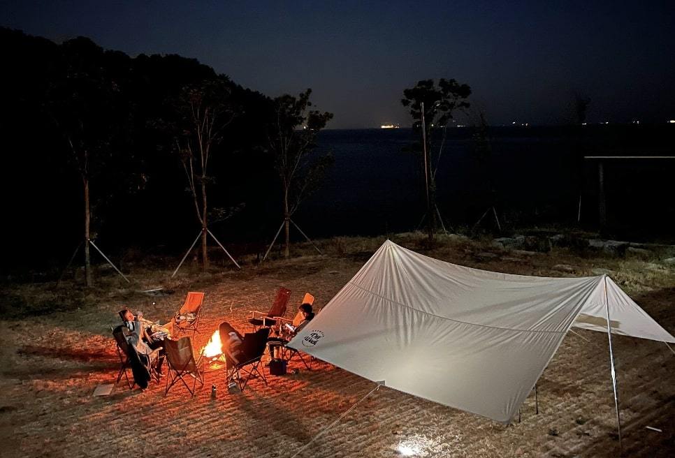 Toss workers taking part in the pilot workcation program gather around a campfire in the southern coastal region of Namhae, South Gyeongsang Province.  (Toss)