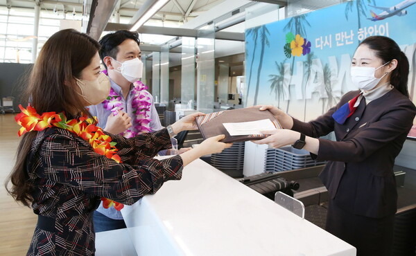 An Asiana Airlines official welcomes passengers on a flight bound for Hawaii, one of the first long-haul routes to resume, at Incheon Airport, Sunday. Asiana Airlines