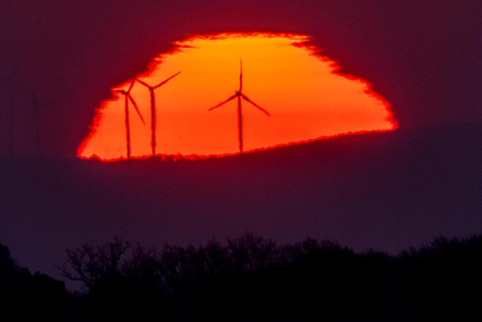 Wind turbines stand in front of the rising sun in Frankfurt, Germany, on March 11, 2022. A United Nation-backed panel plans to release a highly anticipated scientific report on Monday, on international efforts to curb climate change before global temperatures reach dangerous levels. (AP)