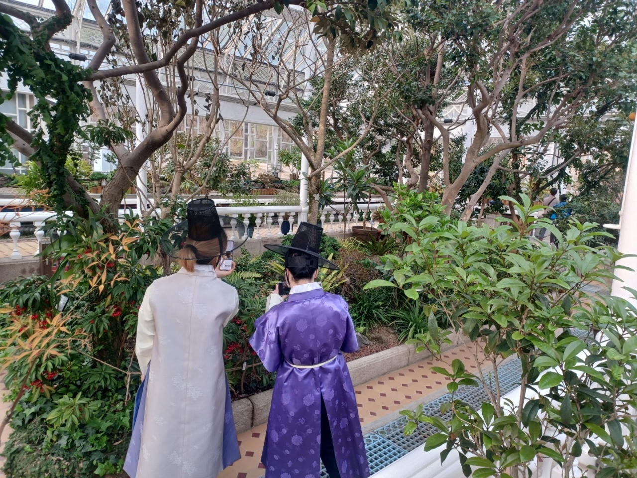 Visitors dressed in hanbok enjoy the Changgyeonggung Grand Greenhouse on April 5.  (Lee Si-jin/The Korea Herald)