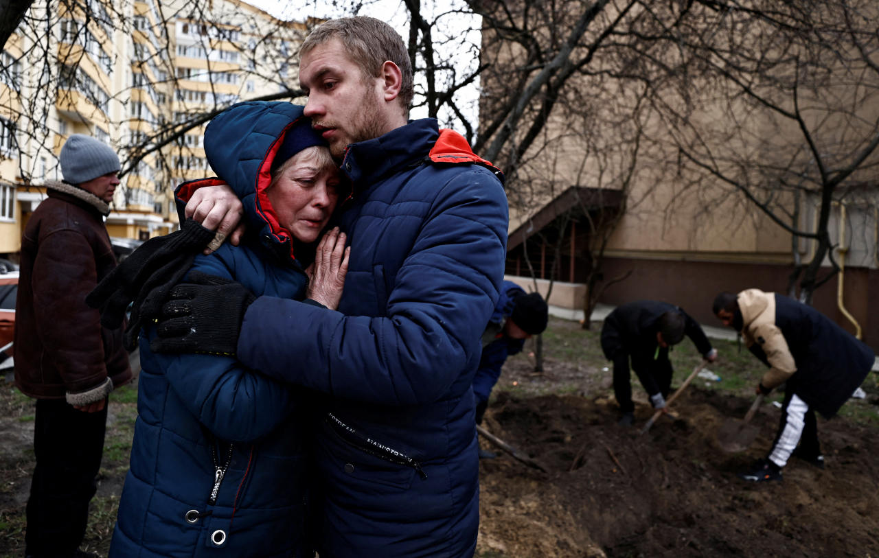 Serhii Lahovskyi (left) hugs Ludmyla Verginska, as they mourn their common friend Igor Lytvynenko, who according to residents was killed by Russian Soldiers, after they found him beside a building's basement, following his burial at the garden of a residential building, in Bucha, Ukraine, Tuesday. (Reuters-Yonhap)