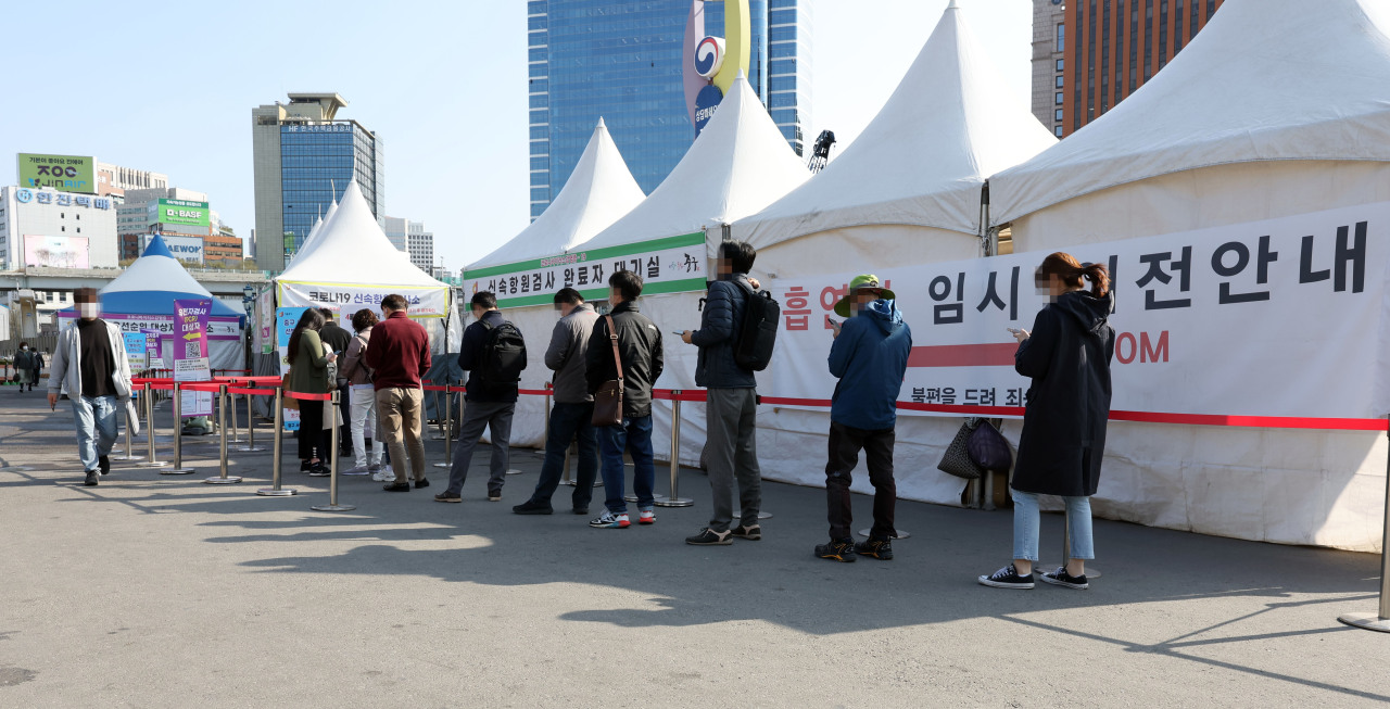 People line up to be tested of COVID-19 at a testing booth near Seoul Station, Thursday. (Yonhap)